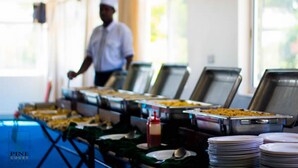Montaje de bufé con varias estaciones de servicio y un chef con uniforme.