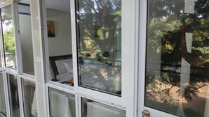 Una habitación con ventanas amplias, una cama y vistas a árboles.