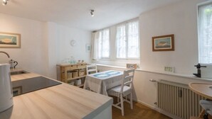Une cuisine équipée d’un évier, d’une table avec des chaises, d’un radiateur et d’une fenêtre avec des rideaux.