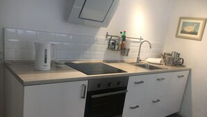 Une cuisine moderne équipée d’un four encastré, d’un évier et d’une bouilloire.