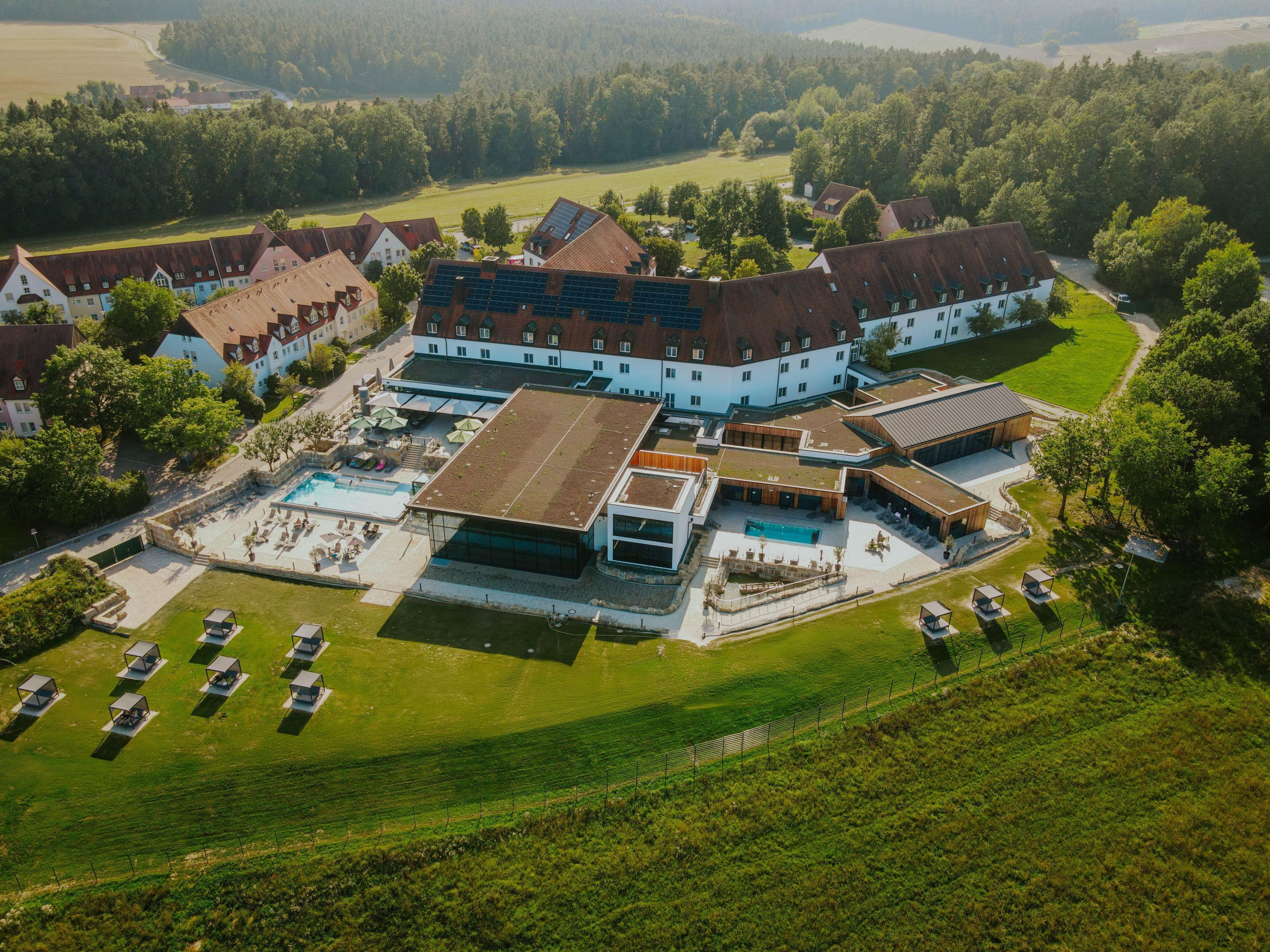 An aerial view of a large estate with multiple buildings, a swimming pool, and a well-maintained lawn.