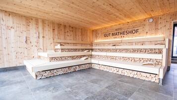Un sauna con paredes de madera y piso de baldosas, que incluye un banco y estantes para toallas.