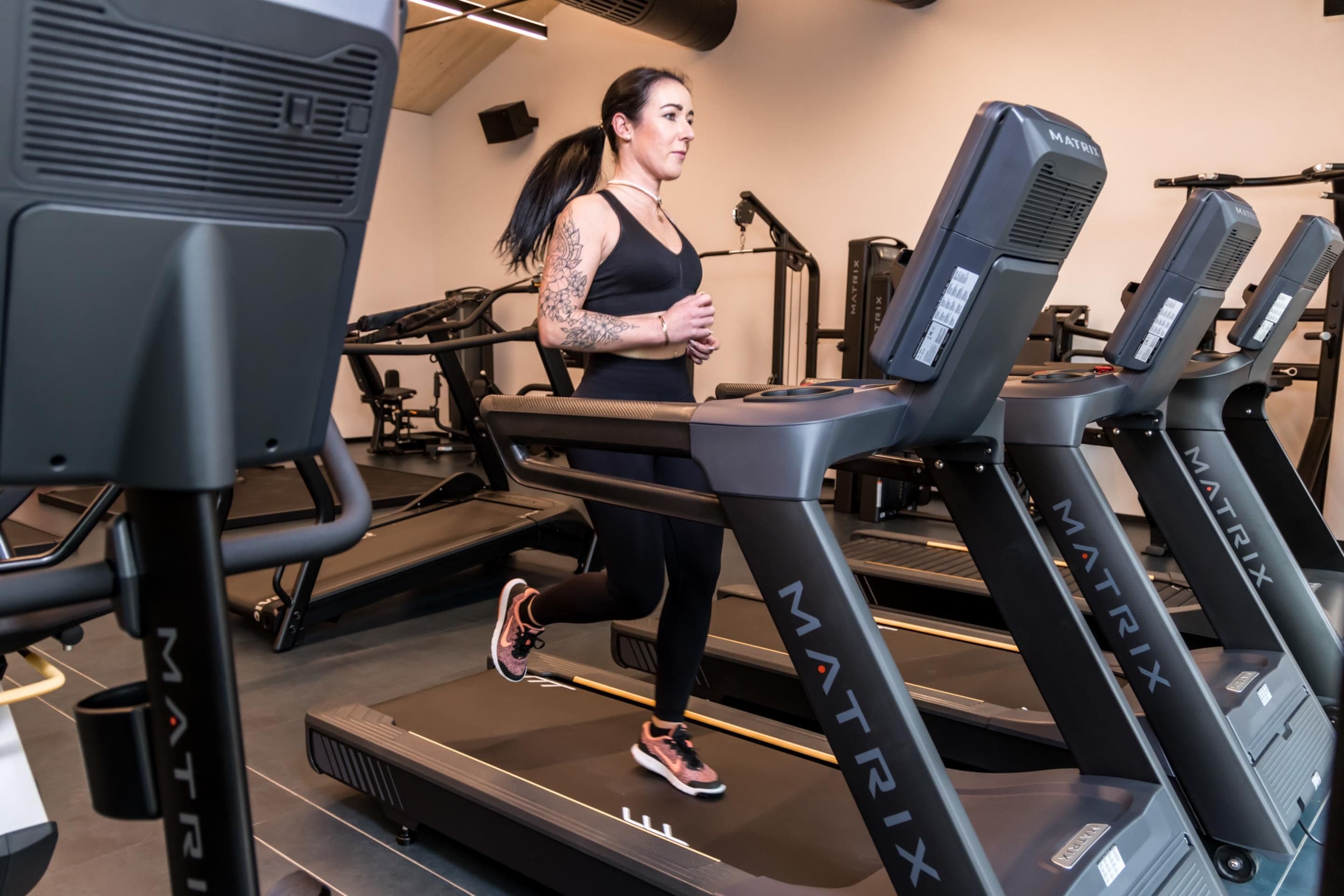 A gym with treadmills, exercise equipment, and a person running on a treadmill.