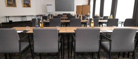A conference room with a long table, multiple chairs, and a large screen at the front.