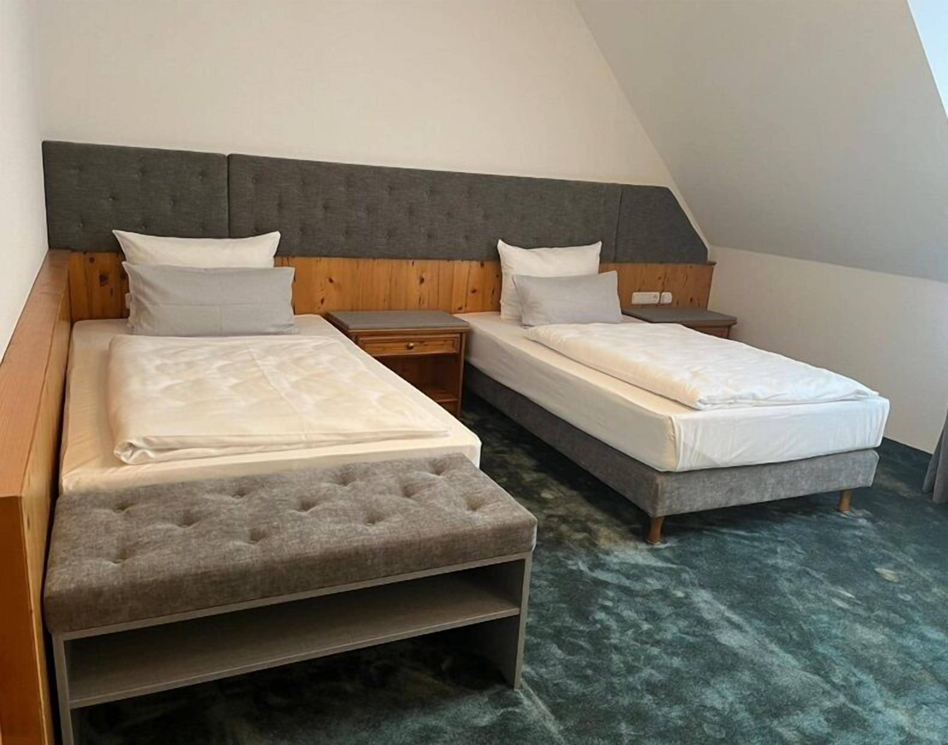 A bedroom with two beds, a wooden headboard, and a green carpet.