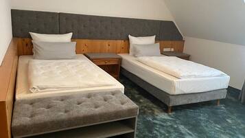 A bedroom with two beds, a wooden headboard, and a green carpet.