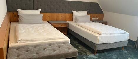 Quarto com duas camas, cabeceira de madeira e tapete verde.