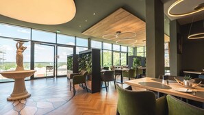 Un comedor moderno con ventanas amplias, una fuente central y muebles contemporáneos.