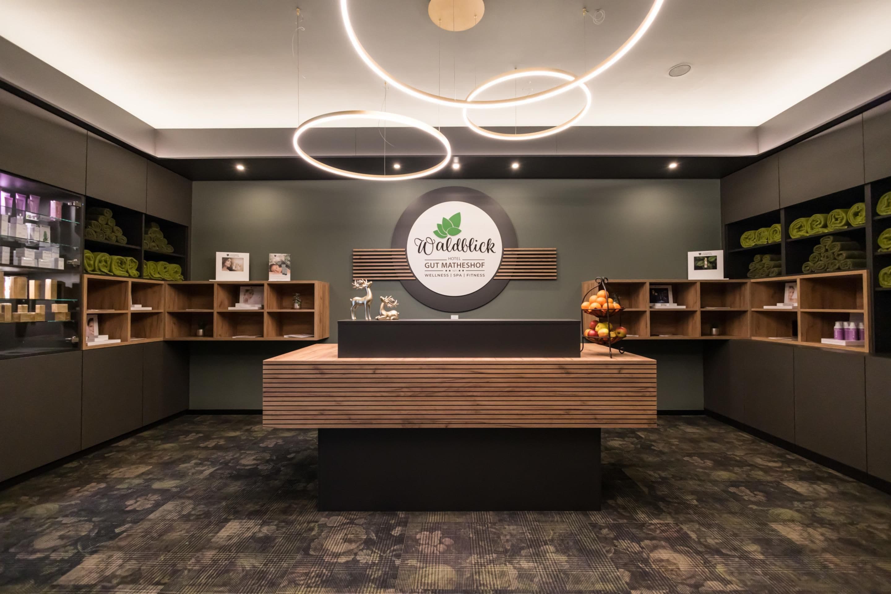 A reception area with a central desk, wooden shelving, and a wall-mounted sign.