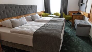A hotel room with a large bed, a desk, two chairs, and a small table.