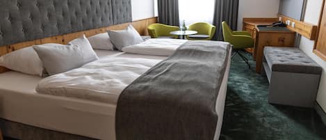 A hotel room with a large bed, a desk, two chairs, and a small table.