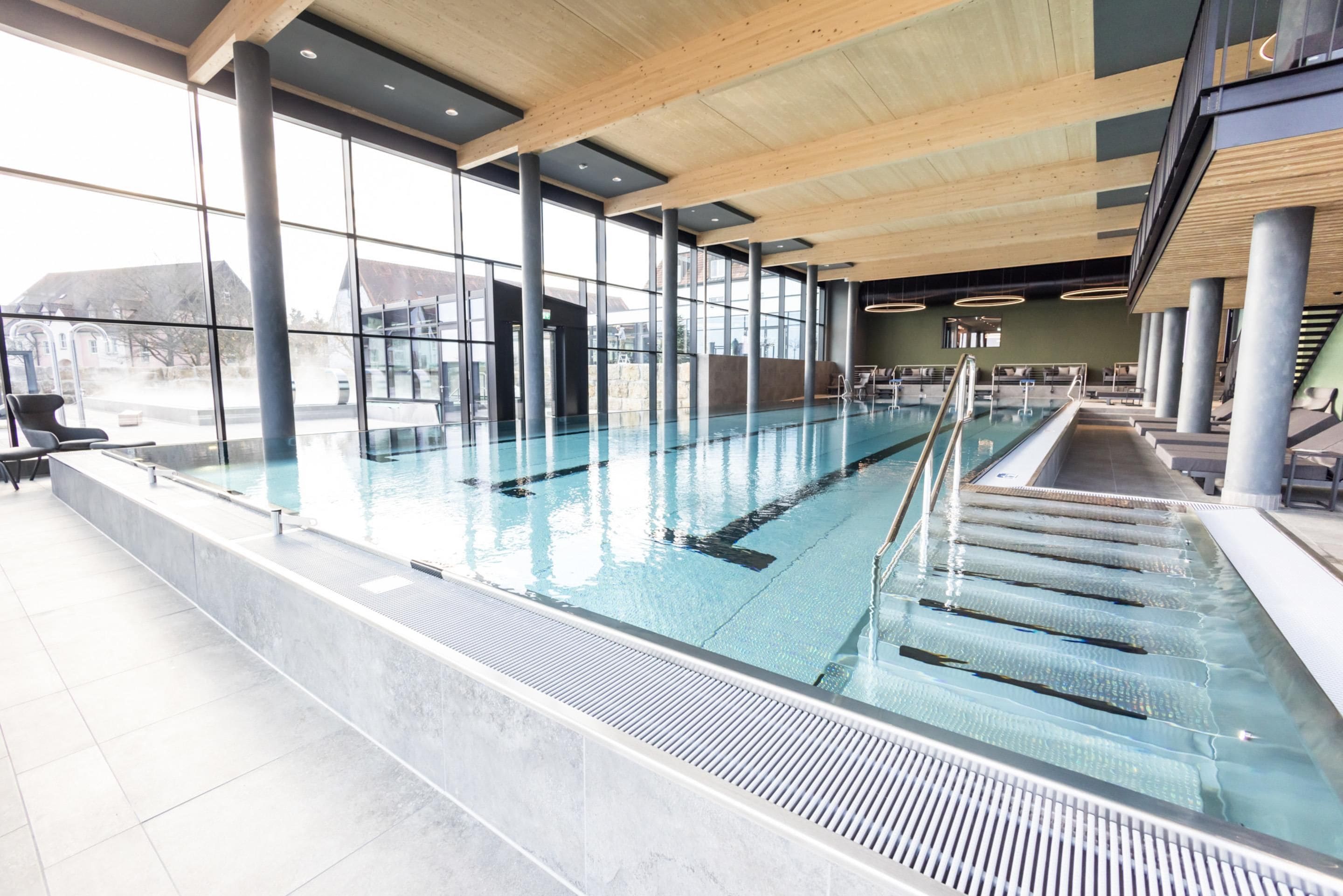 A swimming pool with clear water, surrounded by large windows and modern architecture.