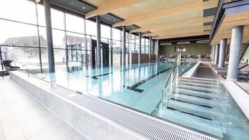 A swimming pool with clear water, surrounded by large windows and modern architecture.