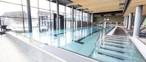 A swimming pool with clear water, surrounded by large windows and modern architecture.