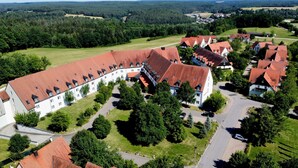 An aerial view of a large, white building with red-tiled roofs, surrounded by greenery and a small parking area. - Hotel & Spa Gut Matheshof, BW Signature Collection (Rieden)