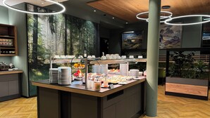 A breakfast bar with a variety of food items, a coffee station, and a large mural of a forest. - Hotel & Spa Gut Matheshof, BW Signature Collection (Rieden)