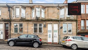 Une rangée de maisons mitoyennes avec une enseigne indiquant « Klass Living » au-dessus de l’entrée.