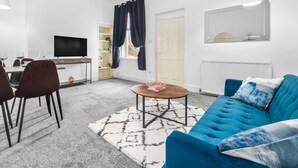 Un salon moderne avec un canapé bleu, une table basse et un téléviseur posé sur un meuble.