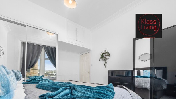 Une chambre moderne avec un grand lit, une armoire, un miroir et une vue sur la ville.