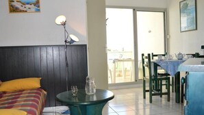 A room with a bed, a table, and a chair. There is a window and a door leading to an outdoor area. - Seaside Apartment with Pool, Parking, and Pets Allowed (Saint-Cyprien)