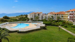 A resort with a swimming pool, multiple-story buildings, and a view of the sea. - Seaside Apartment with Pool, Parking, and Pets Allowed (Saint-Cyprien)