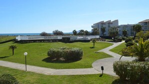 A hotel with a well-maintained lawn, a pathway, and a view of the ocean. - Seaside Apartment with Pool, Parking, and Pets Allowed (Saint-Cyprien)