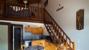 Una cocina amplia con armarios de madera, una mesa de comedor con sillas y una escalera de madera.