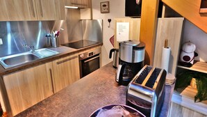 A modern kitchen with stainless steel appliances, wooden cabinets, and a built-in toaster. - Charming 2-Room Mezzanine Apt in Grand-Bornand Village, Sleeps 4, Balcony, Steps from Ski Lifts (Le Grand-Bornand)