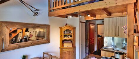 Une cuisine chaleureuse avec des meubles de rangement en bois, une table à manger et un ventilateur de plafond.