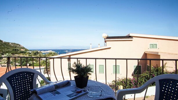 A balcony with a table, chairs, and a potted plant.