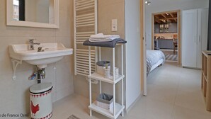 A modern bathroom with a sink, mirror, towel rack, and storage shelves.