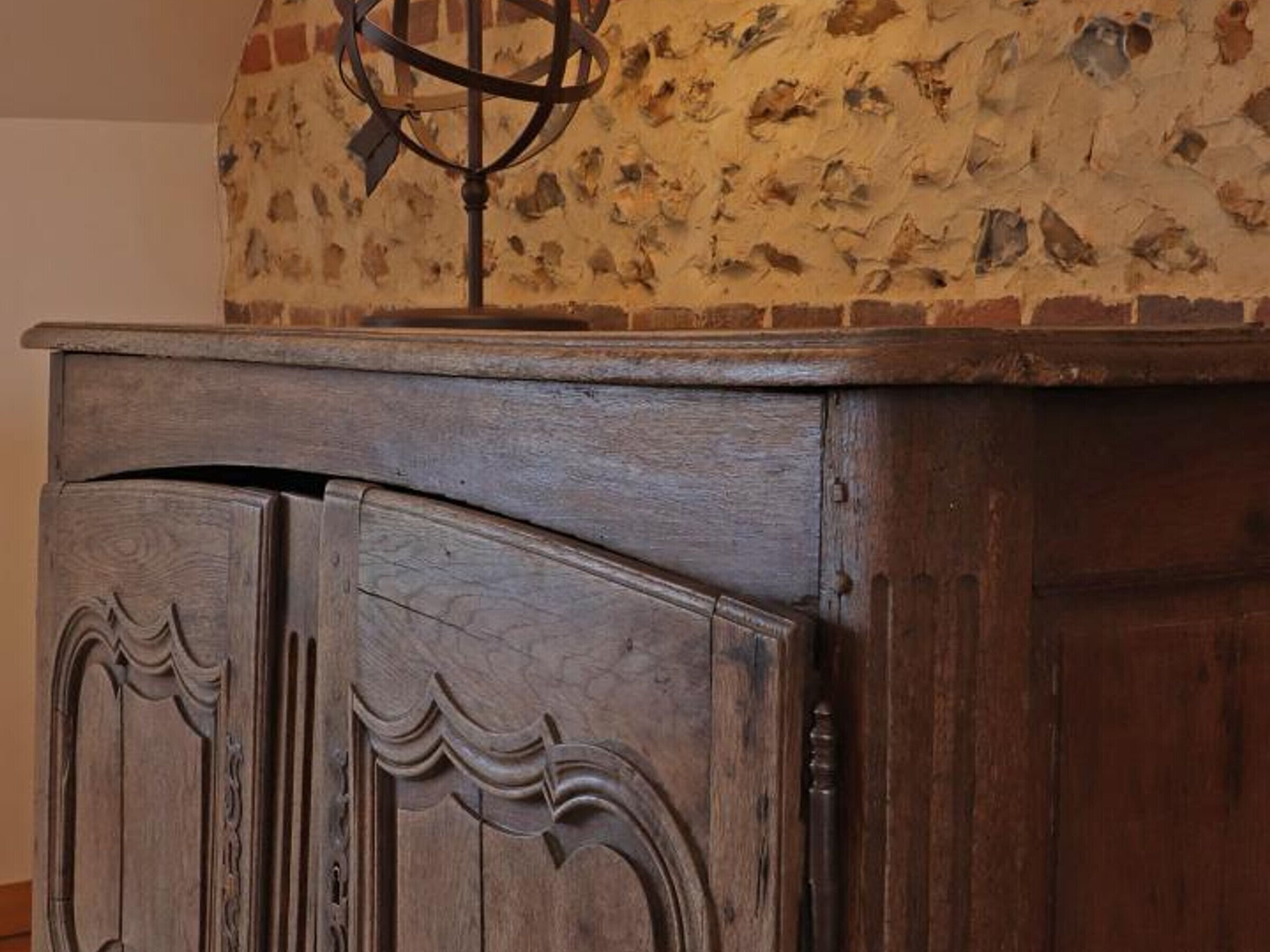 Een houten kast met gedetailleerd snijwerk en een wereldbol bovenop.