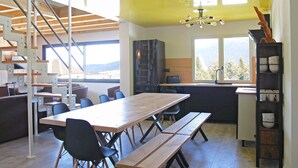 Une cuisine moderne avec une table et des bancs en bois, un escalier et une vue sur l’extérieur.