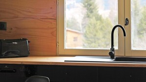 Une cuisine dotée d’un plan de travail en bois, d’un robinet noir et d’une fenêtre offrant une vue sur les montagnes.