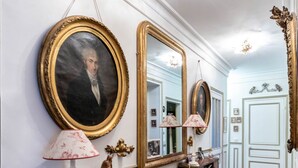 Un couloir agrémenté de miroirs décoratifs, une console en marbre et un plancher en bois.