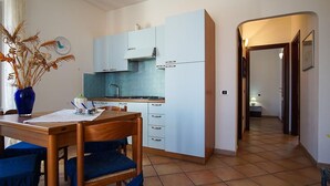 A compact kitchen with light blue cabinets, a wooden dining table, and chairs. - Rena Bianca Apartment 40m from the beach No. DAR-T5 (Santa Teresa Gallura)
