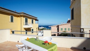 Un balcone con un tavolo apparecchiato per due, vista sulla costa.