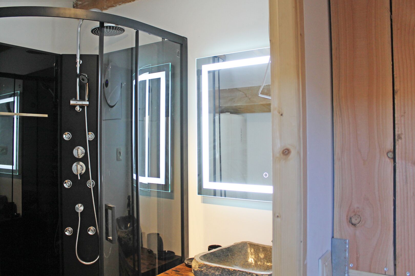 A bathroom with a glass shower enclosure, a sink, and a window.