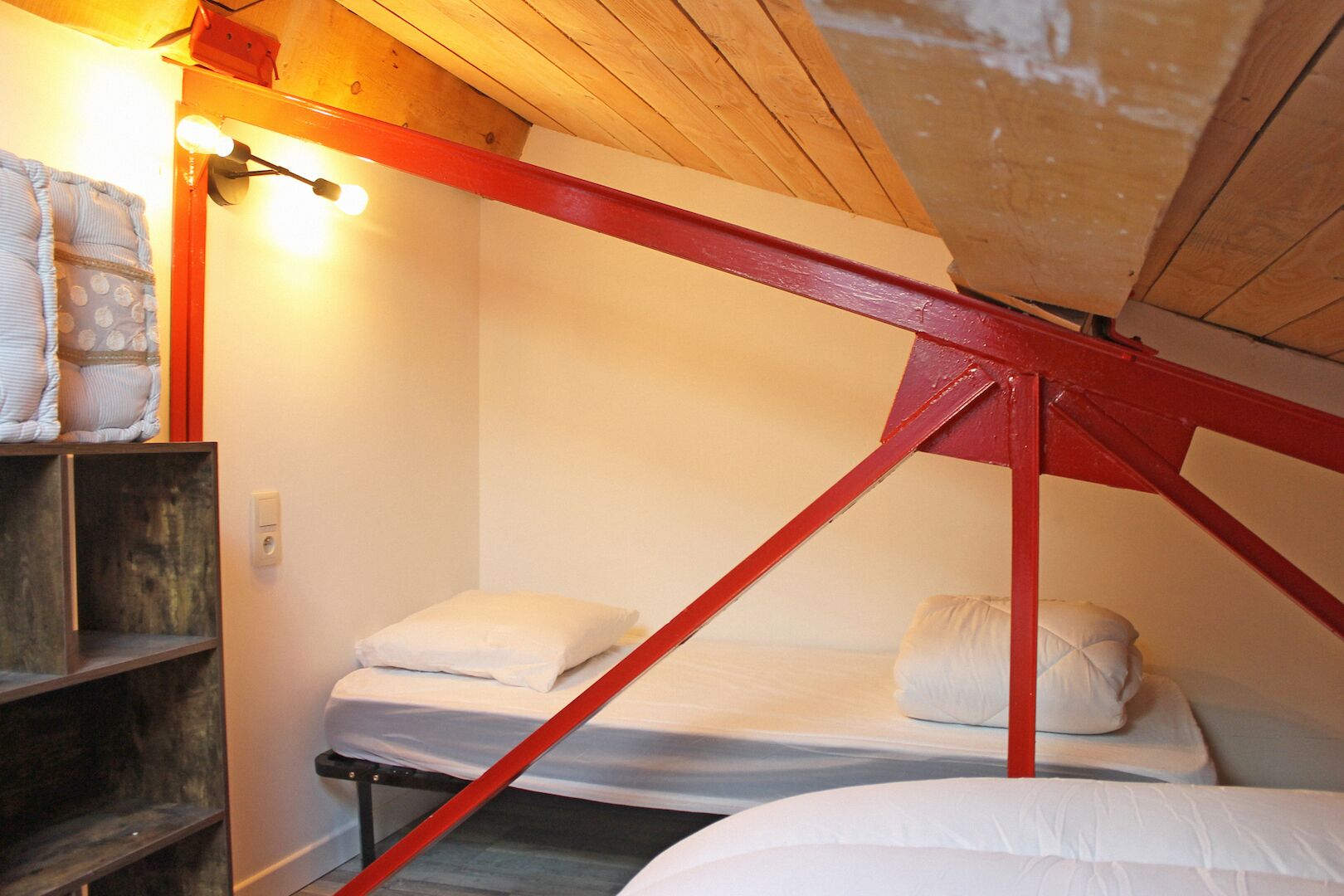 A small, cozy room with a bunk bed and a shelf with pillows.
