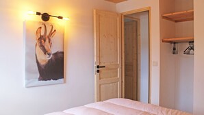 Un dormitorio con cama, una puerta y una lámpara fijada a la pared.