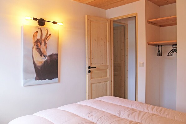 Quarto com cama, uma porta e luminária fixada na parede.