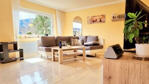 A living room with a sofa, coffee table, and a TV stand with a plant.