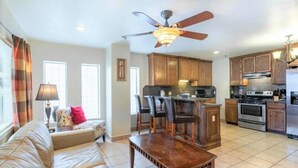 A modern kitchen with wooden cabinets, a central island, and a dining area with a table and chairs. - Lantana Retreat 3 - Spacious 3BR w/ Pool (South Padre Island)