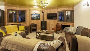 Ein gemütliches Wohnzimmer mit Holzwänden, einem Kamin und einem Fernseher.