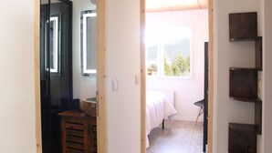 Ein Schlafzimmer mit Bett, Fenster und Blick auf Grün.