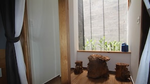 Una habitación con un ventanal grande, suelo de madera y dos taburetes de madera.