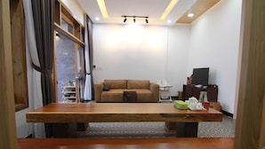 Una sala de estar moderna con una mesa de comedor de madera, un sofá, un televisor y una pequeña área de cocina.