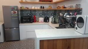 Una cocina compacta equipada con lavadora, microondas, cafetera y tostadora.