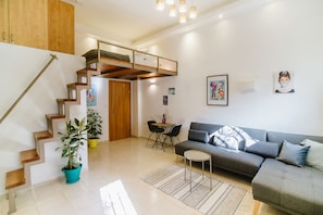 Una sala de estar moderna con una escalera, un sofá, una mesa de comedor y una planta en maceta.