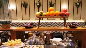 Montaje de bufé con diferentes alimentos y una pared decorativa con plantas enmarcadas.